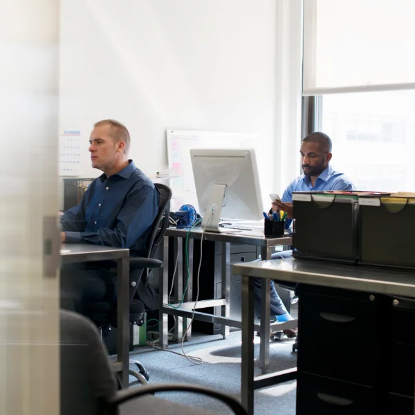 Two men working in an office, using computer to carry out assessment